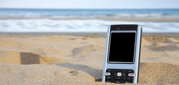 tech on vacation cell phone in sand