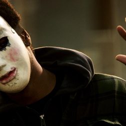 A man wearing a mask with the word God on it in The Purge Anarchy.