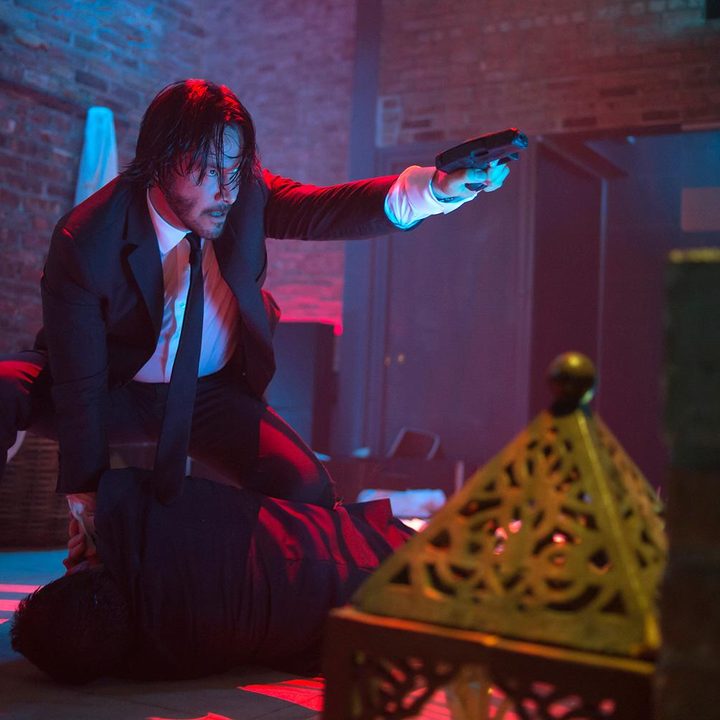 John Wick holds a gun and points it.