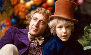 Willy Wonka sits next to a young boy.