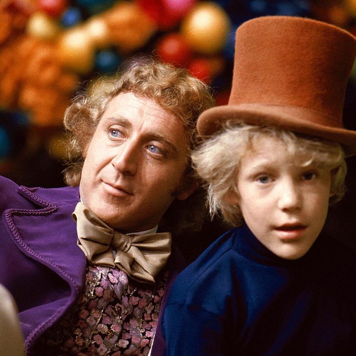 Willy Wonka sits next to a young boy.