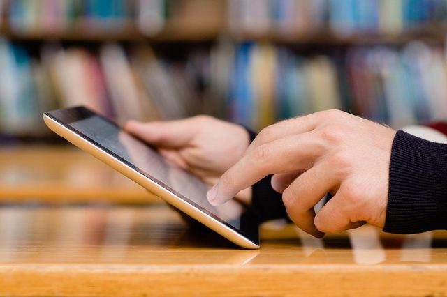 Hands typing on notebook in library