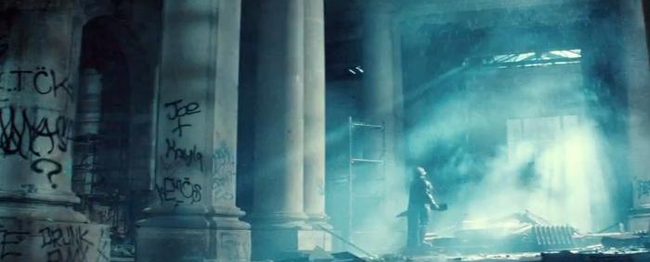 Batman stands somewhere in ruins.