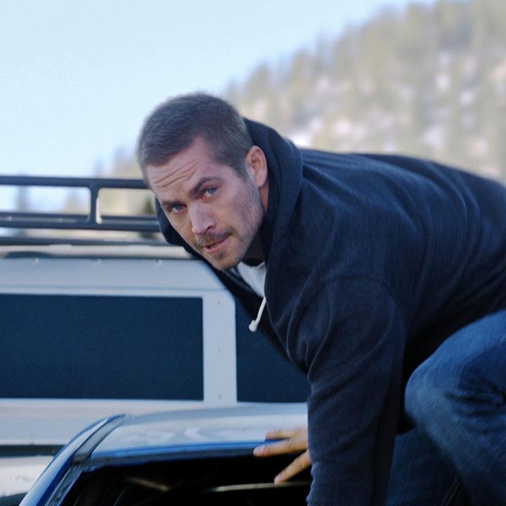 Paul Walker stands on the edge of a bus in Furious 7.