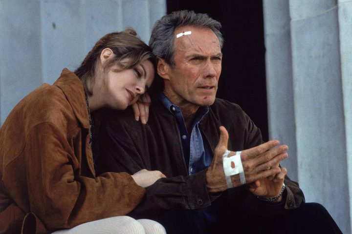 A woman rests on the shoulder of Clint Eastwood.