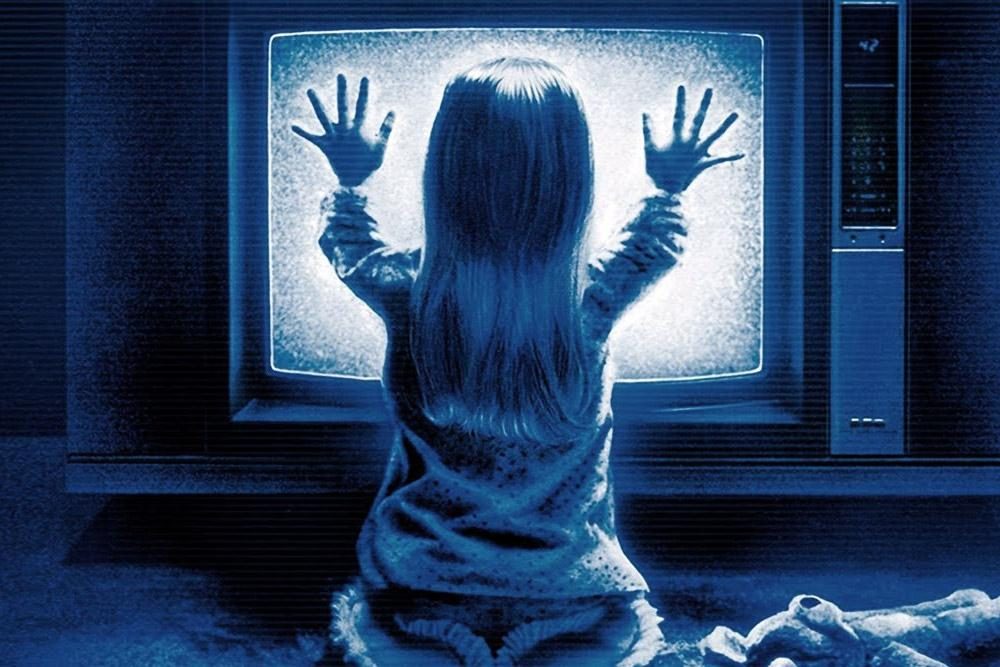 Carol Anne touching a TV in a promotional image for Poltergeist.