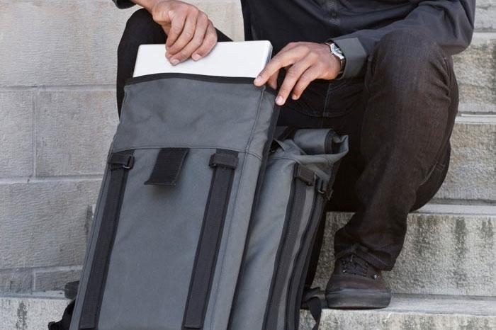 Close up of a person's hands pulling a white item out of a Mission Workshop&nbsp;R6 Arkiv Field Pack.