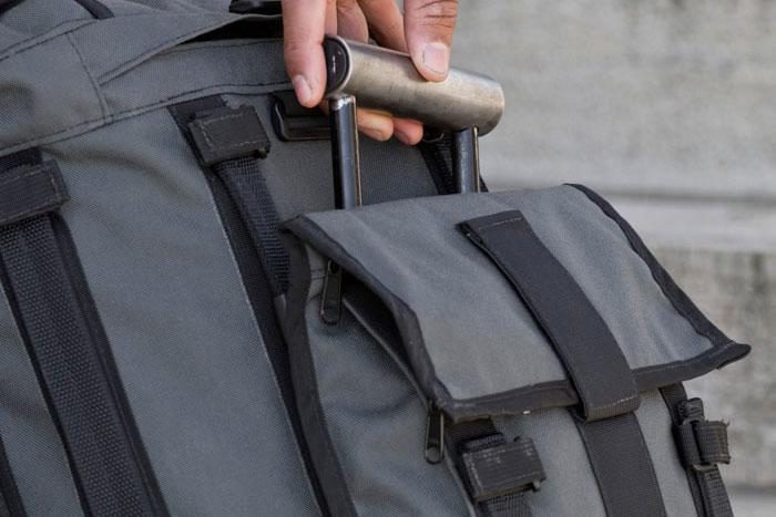 Profile view of a person's hand holding a handle from a Mission Workshop&nbsp;R6 Arkiv Field Pack.