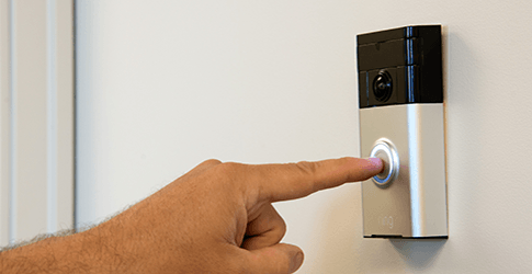 A finger pressing a Ring Video Doorbell.