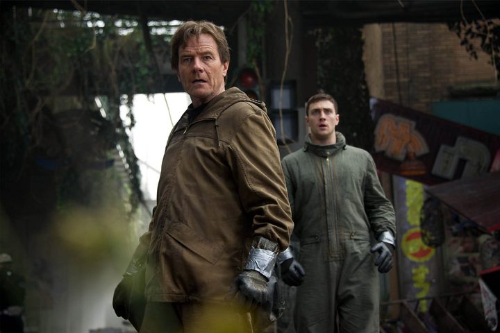 Two men in hazmat suits look back and stare.