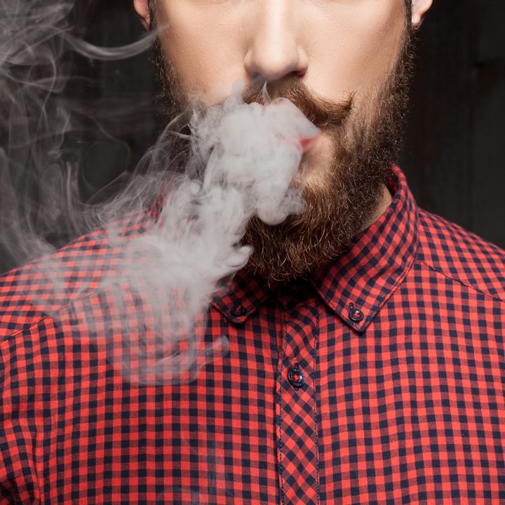 Cheerful young guy with beard is smoking