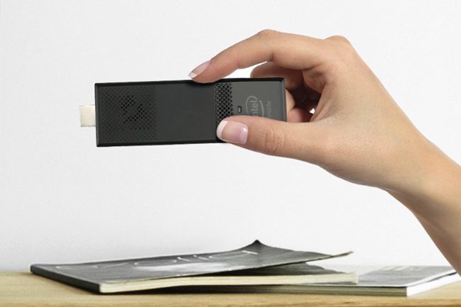 A person holding an Intel Compute Stick above a desk.