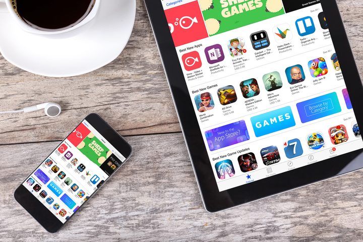 iPhone and iPad rest on a table, each with the App Store open.