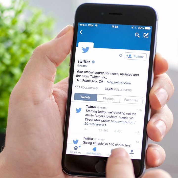 Man holding iPhone 6 with Twitter on the screen
