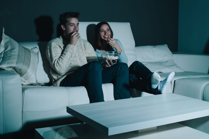 couple enjoying watching a movie at home laughing on the couch