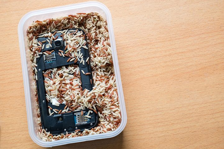 62051475 - mobile phone in milled brown rice. save wet phone.