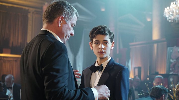 Sean Pertwee and David Mazouz as Alfred and Bruce Wayne at a party in the TV show Gotham.