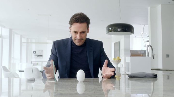 Jon Hamm looking at an egg-like object on a table in Black Mirror.