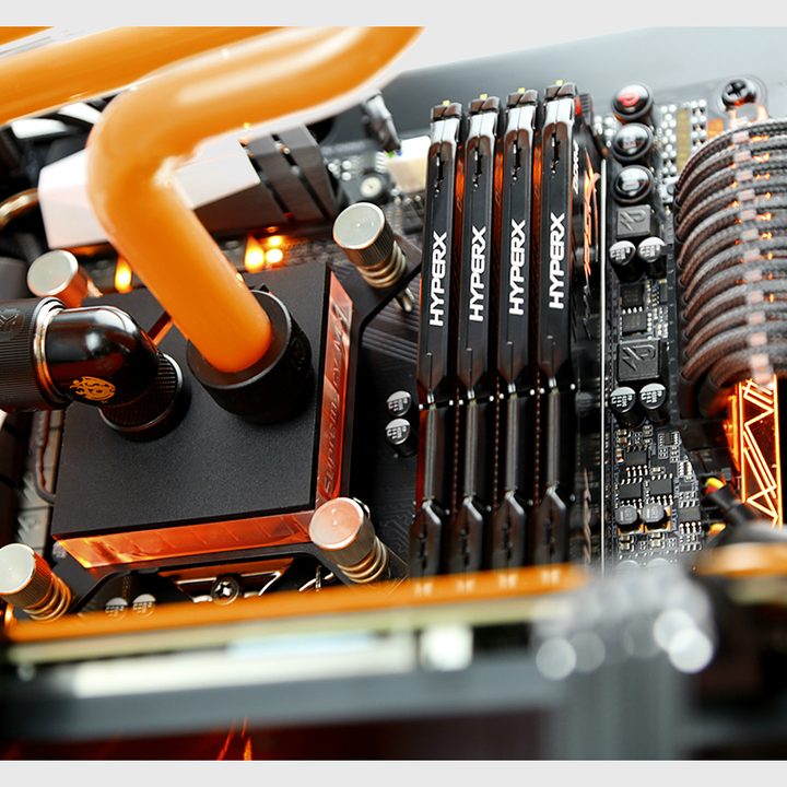 A motherboard fitted with a water cooling CPU block and four sticks of RAM.