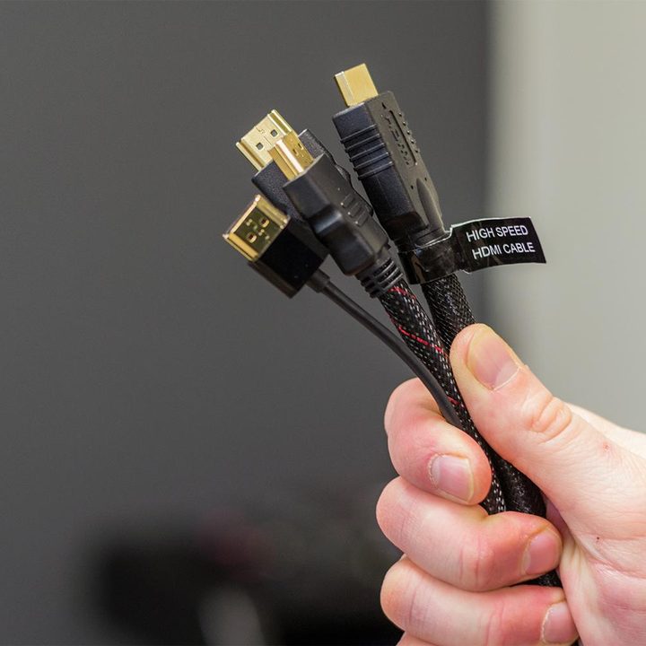 Three HDMI cables held in someone's hand.