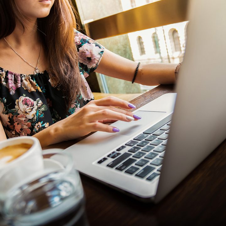 Woman using a laptop next to a latte.