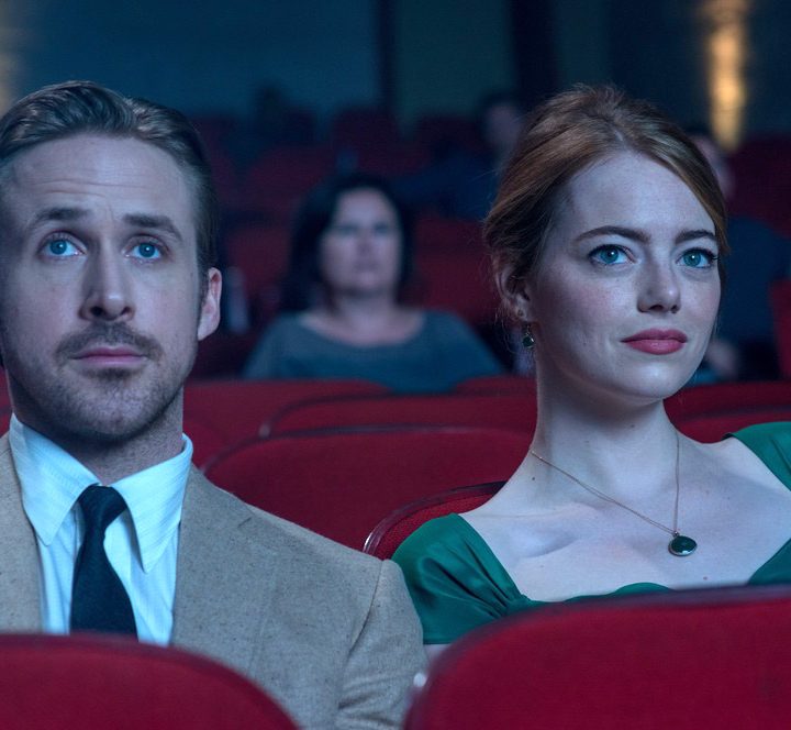 Ryan Gosling and Emma Stone sit next to each other in a theater.