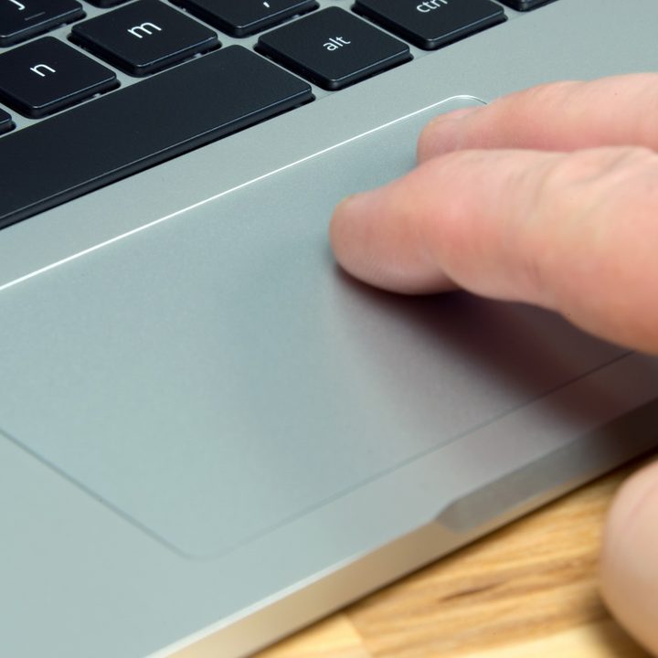 A person tapping the touchpad of an ASUS Chromebook Flip C302CA with two fingers.