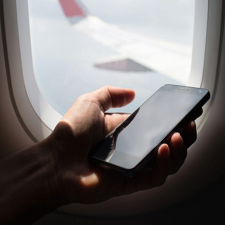 Person holding their smartphone on a plane.