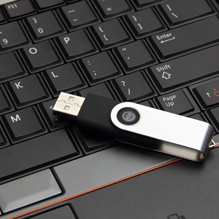 A flash drive sitting on top of a keyboard.