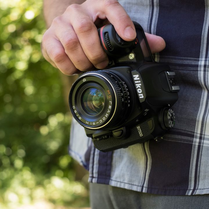 The D7500 held with one hand facing the front of the camera