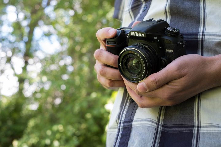 The D7500 being held with two hands facing the camera
