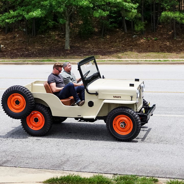 Side shot of beige classic jeep with spare wheel on back