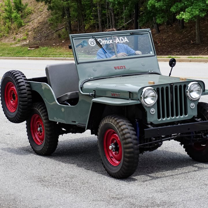Side shot of teal classic jeep with spare tire on the back