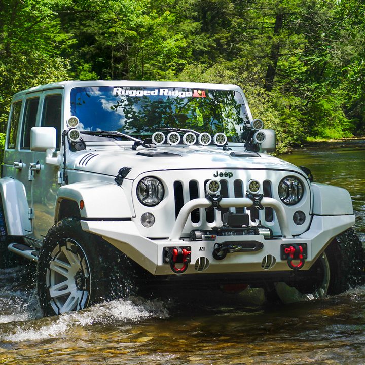 White Jeep Wrangler Unlimited driving through a creekbed