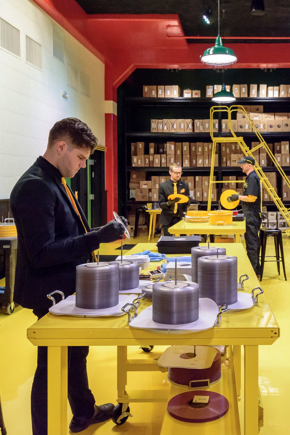 man-placing-records-into-covers-with-stacks-of-vinyl-around-vertical