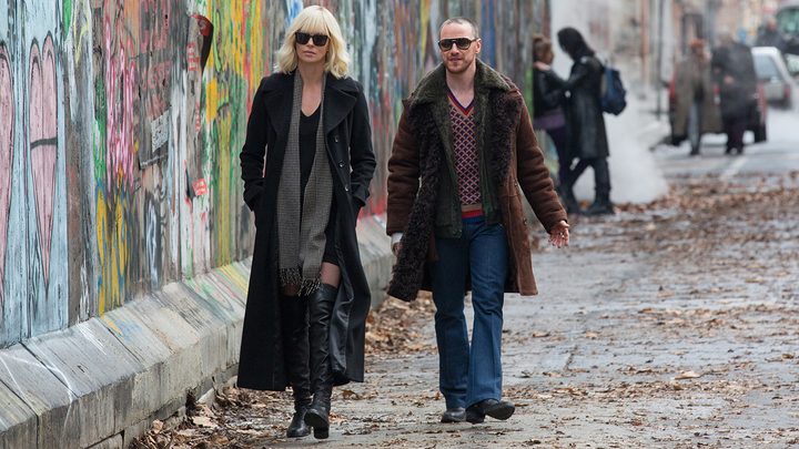 A man and woman walk down a street.