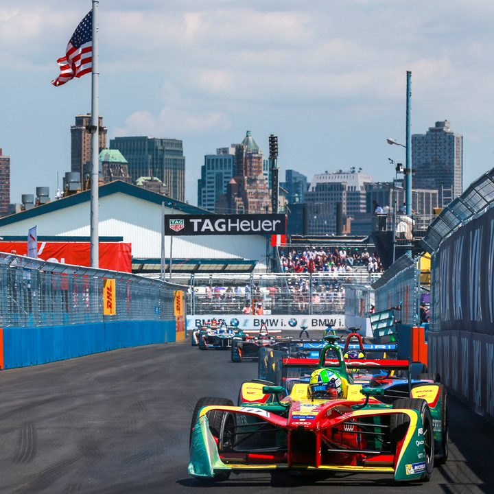Formula E racers coming down the front stretch with NYC in the background at the ePrix