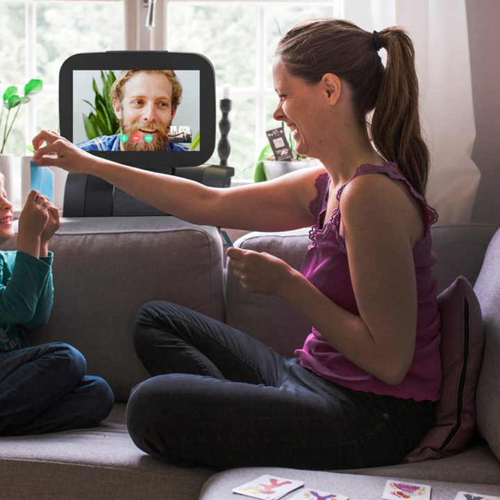 A woman and child high-fiving while on video chat with a man smiling