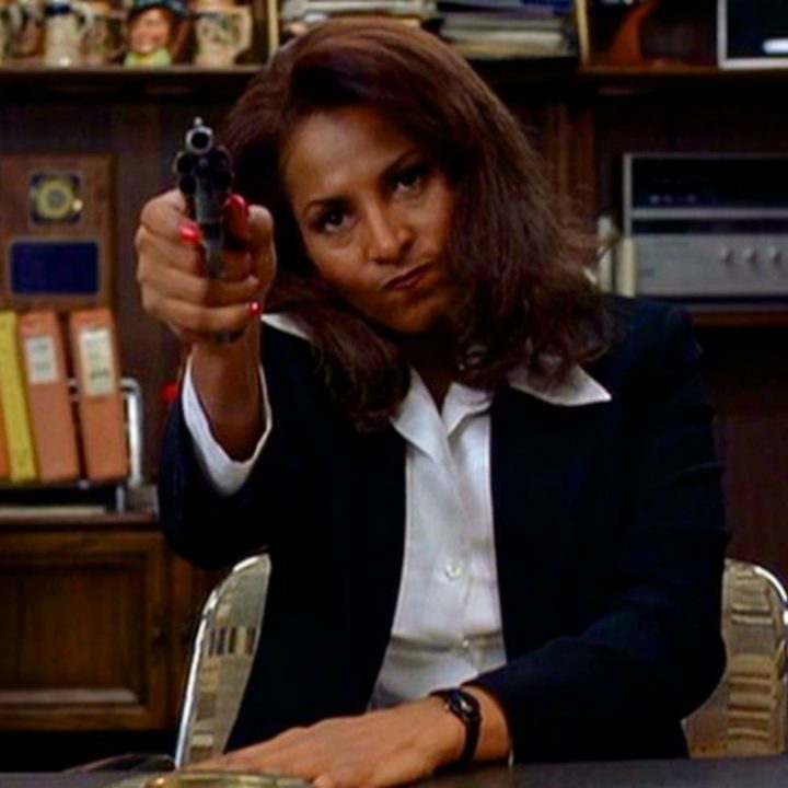 A woman points a gun while sitting down.