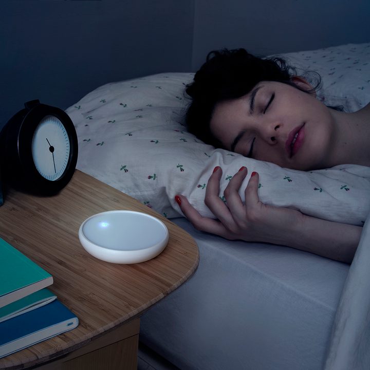 Dodow sleep aid on night table in the dark.
