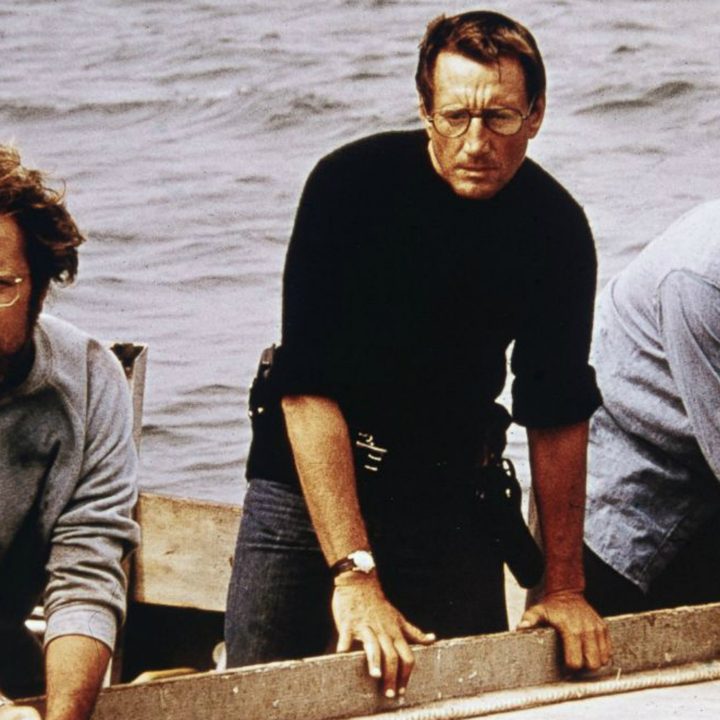 Three men stand in a boat and stare into the ocean in Jaws.