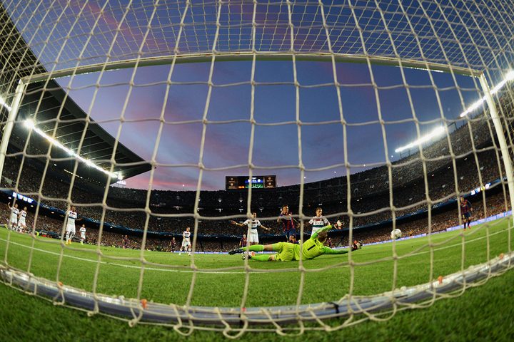 A soccer goal net with the rest of the pitch in front.