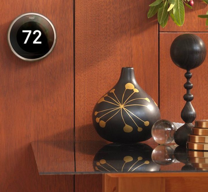 Nest learning thermostat on a wood wall.