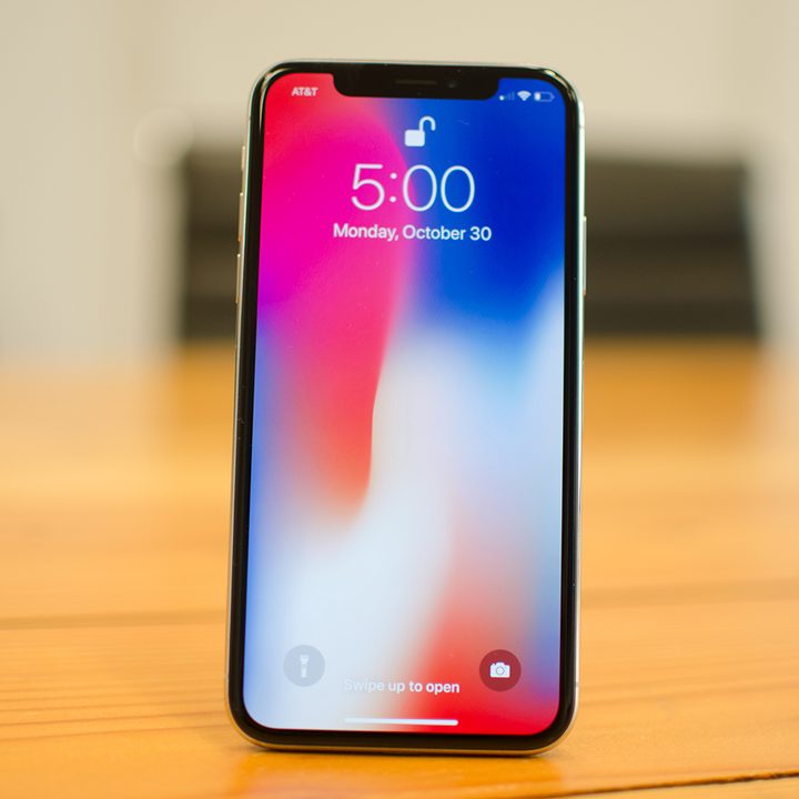 Thw Apple iPhone X standing upright on a table.