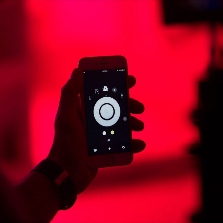 Holding a smartphone with a lighting app for adjusting lights.