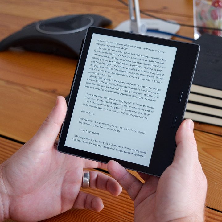 A man reads a text on an Amazon Kindle Oasis.