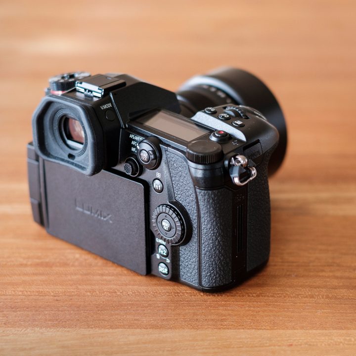Panasonic Lumix G9 Review | Camera sitting on a table facing the top right corner of the frame, showing the back of the camera at an angle