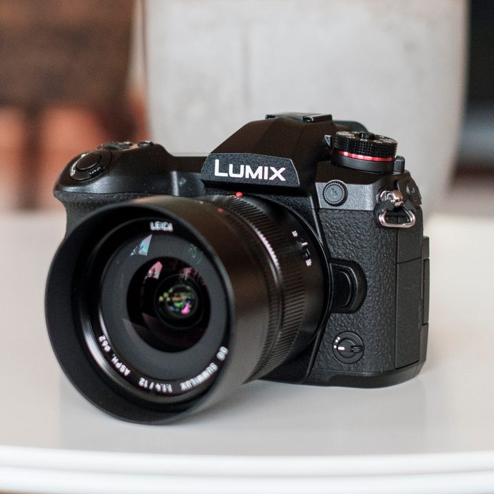 Panasonic Lumix G9 Review | Hero shot of the camera sitting on a white table facing the left side of the frame