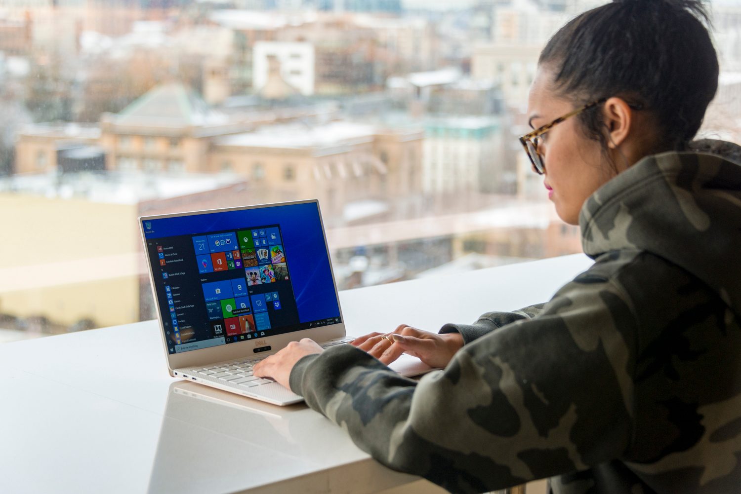 Dell XPS 13 9370 review | Hero shot of woman using computer at a table in front of a window