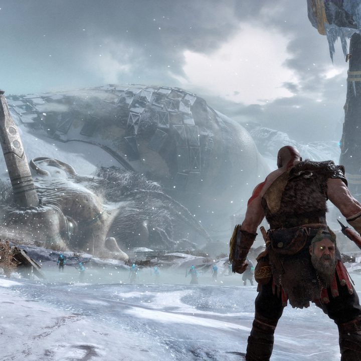 God of War Review | Kratos and Atreus looking down a snowy mountain pass with a dead titan forming the ridgeline